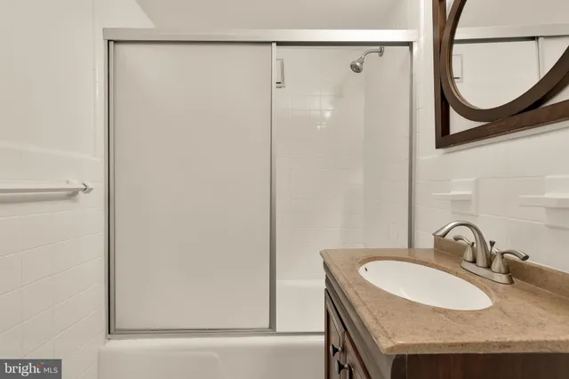a bathroom with a granite countertop shower a mirror and a sink