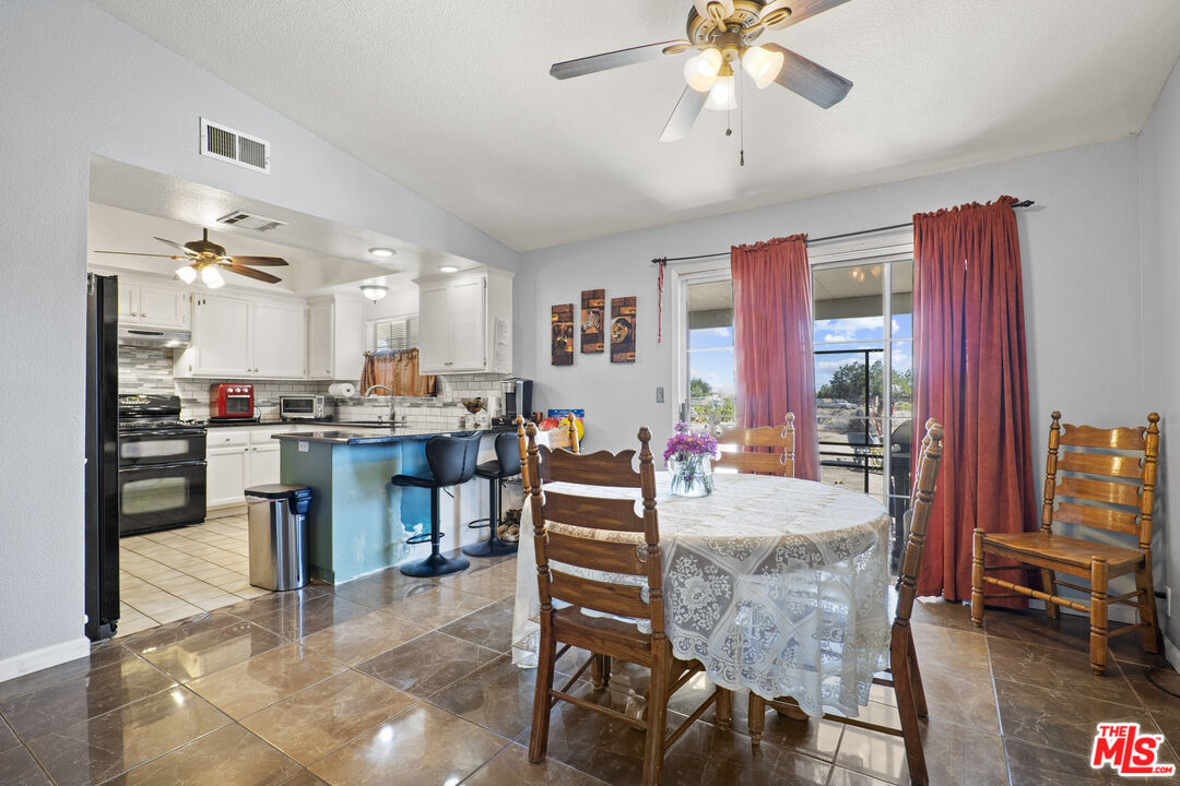 10647 East Ave R 10 Littlerock, CA 93543 - Photo 25 of 34 a large kitchen with a table chairs stainless steel appliances and cabinets