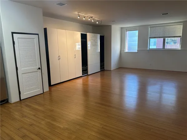 an empty room with wooden floor and windows