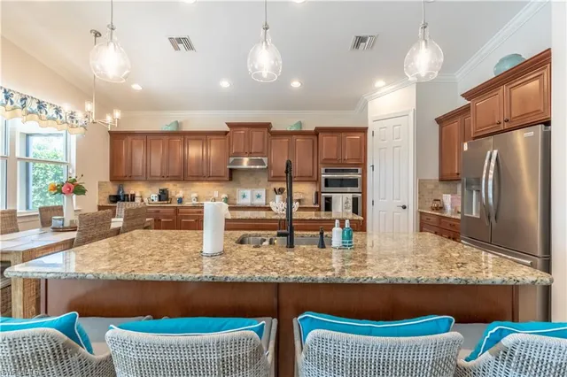 a kitchen with granite countertop kitchen island stainless steel appliances a stove refrigerator sink and microwave