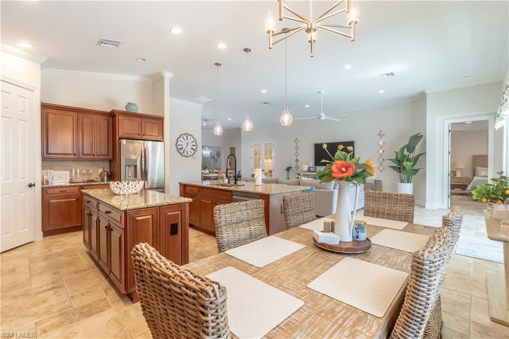 9332 Fieldstone Lane Naples, FL 34120 - Photo 16 of 41 a kitchen with stainless steel appliances kitchen island granite countertop a refrigerator a stove top oven and a dining table with wooden floor