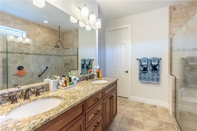a bathroom with a granite countertop double vanity sink a mirror and shower