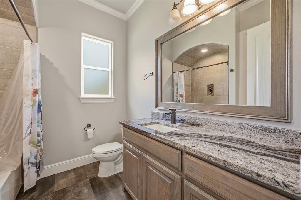 9503 Bellechase Road Granbury, TX 76049 - Photo 25 of 40 a bathroom with a granite countertop sink a toilet and a mirror