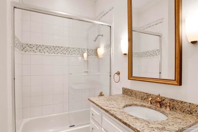 a bathroom with a granite countertop sink a mirror a bathtub and shower