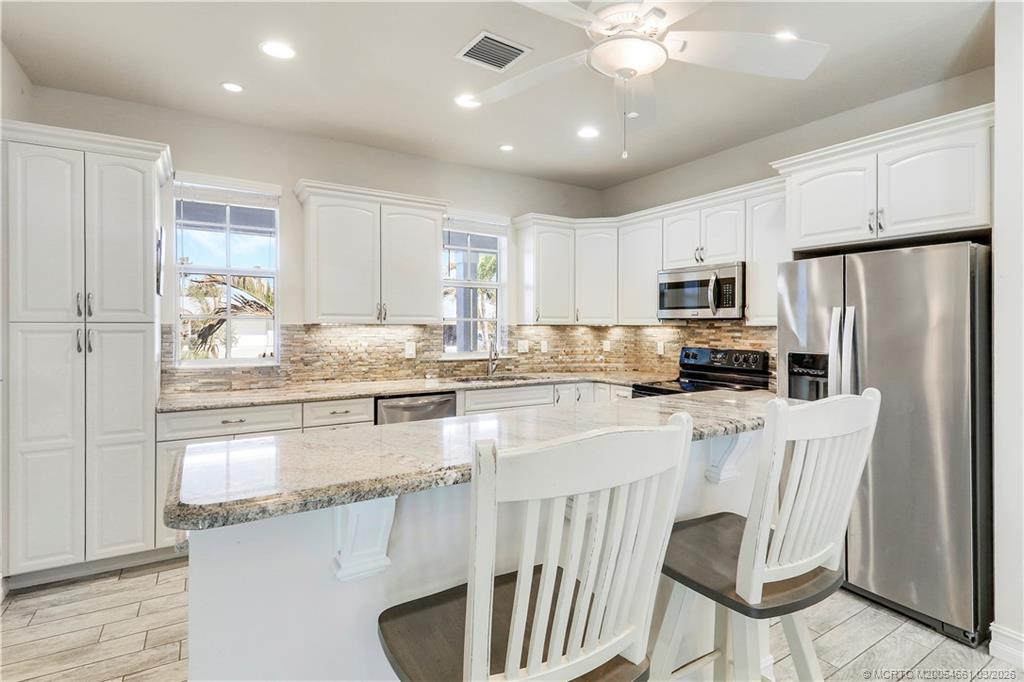 5352 Southeast Nassau Terrace Stuart, FL 34997 - Photo 14 of 53 a kitchen with stainless steel appliances granite countertop a refrigerator a stove a sink cabinets and a dining table