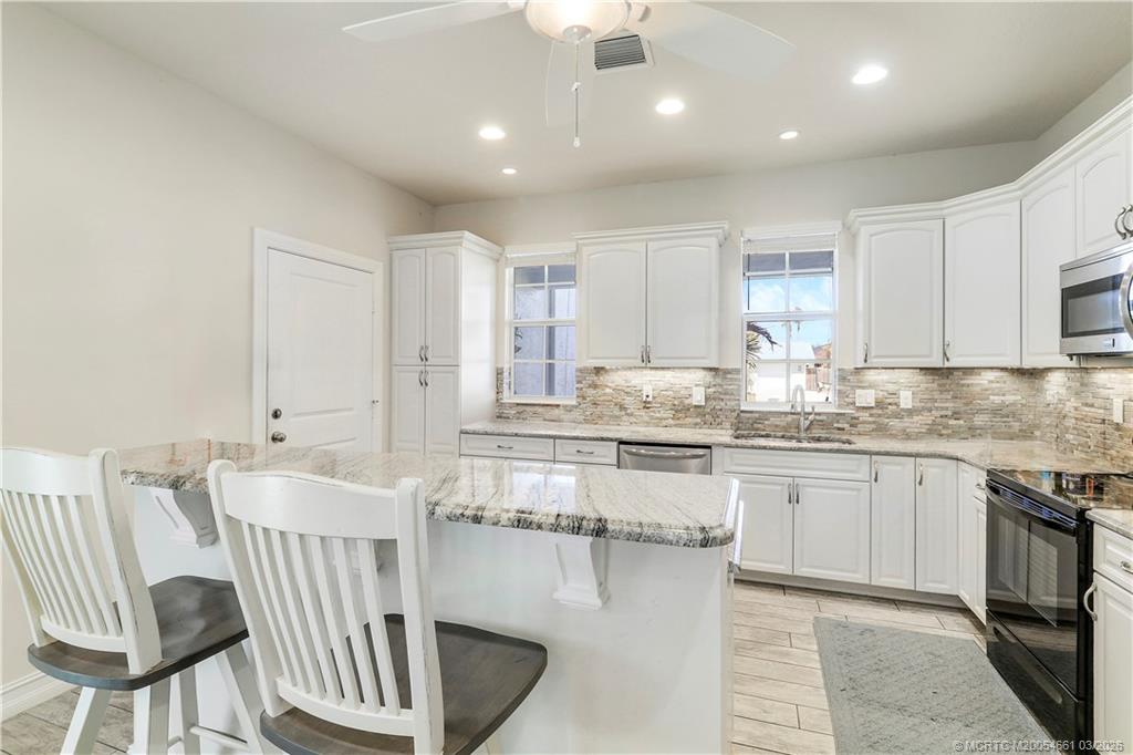 5352 Southeast Nassau Terrace Stuart, FL 34997 - Photo 15 of 53 a kitchen with kitchen island granite countertop lots of counter top space and microwave