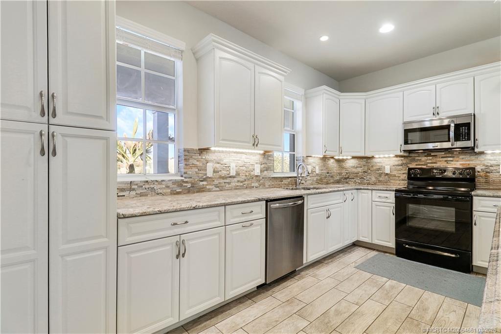 5352 Southeast Nassau Terrace Stuart, FL 34997 - Photo 16 of 53 a kitchen with granite countertop white cabinets and stainless steel appliances