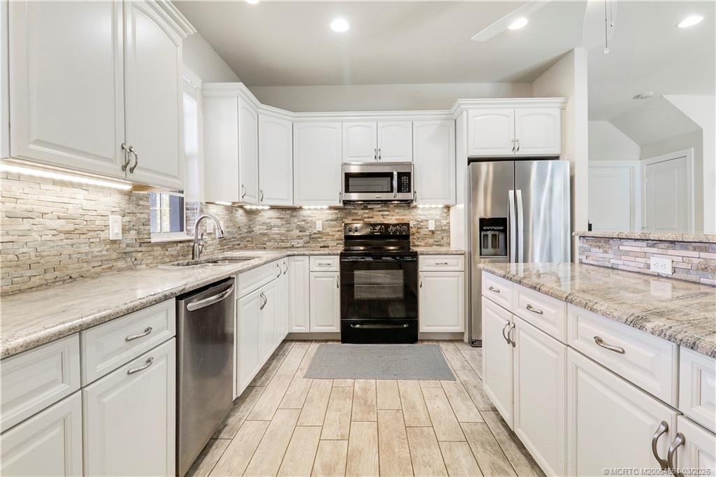 5352 Southeast Nassau Terrace Stuart, FL 34997 - Photo 17 of 53 a kitchen with stainless steel appliances granite countertop a stove top oven a refrigerator a sink and dishwasher with white cabinets
