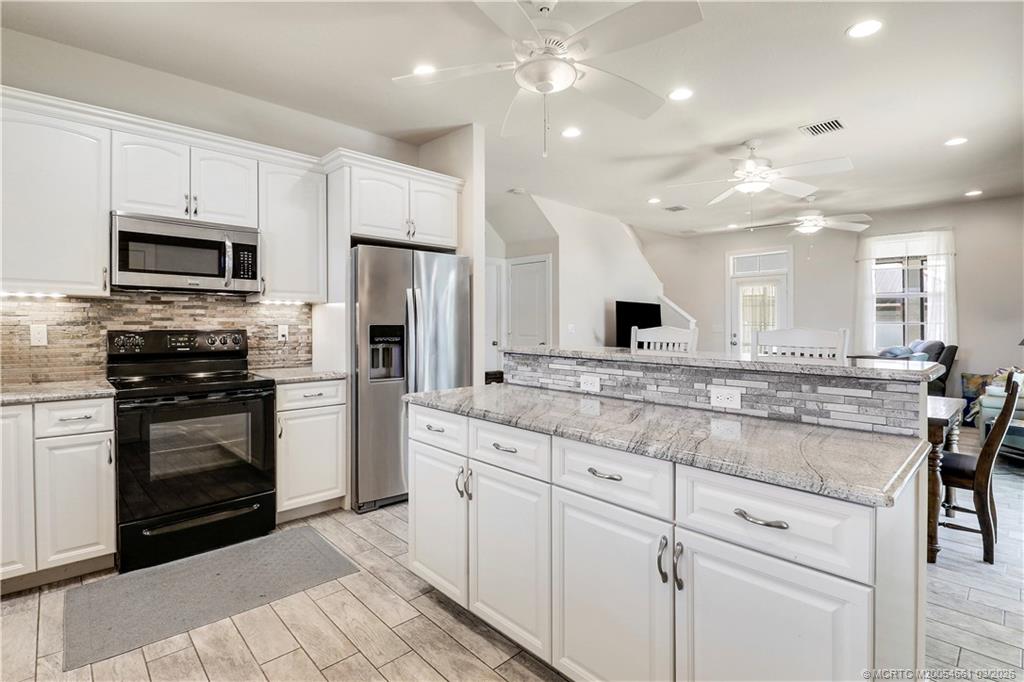 5352 Southeast Nassau Terrace Stuart, FL 34997 - Photo 18 of 53 a kitchen with stainless steel appliances kitchen island granite countertop a stove top oven a sink and dishwasher