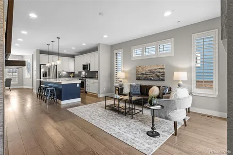 a living room with furniture and kitchen view with wooden floor