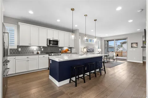 a kitchen with stainless steel appliances granite countertop a table chairs sink refrigerator and cabinets