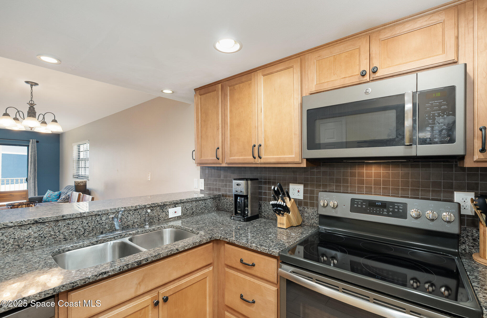 5350 Ocean Beach Boulevard, Unit 211 Cocoa Beach, FL 32931 - Photo 15 of 37 a kitchen with stainless steel appliances granite countertop a sink and cabinets
