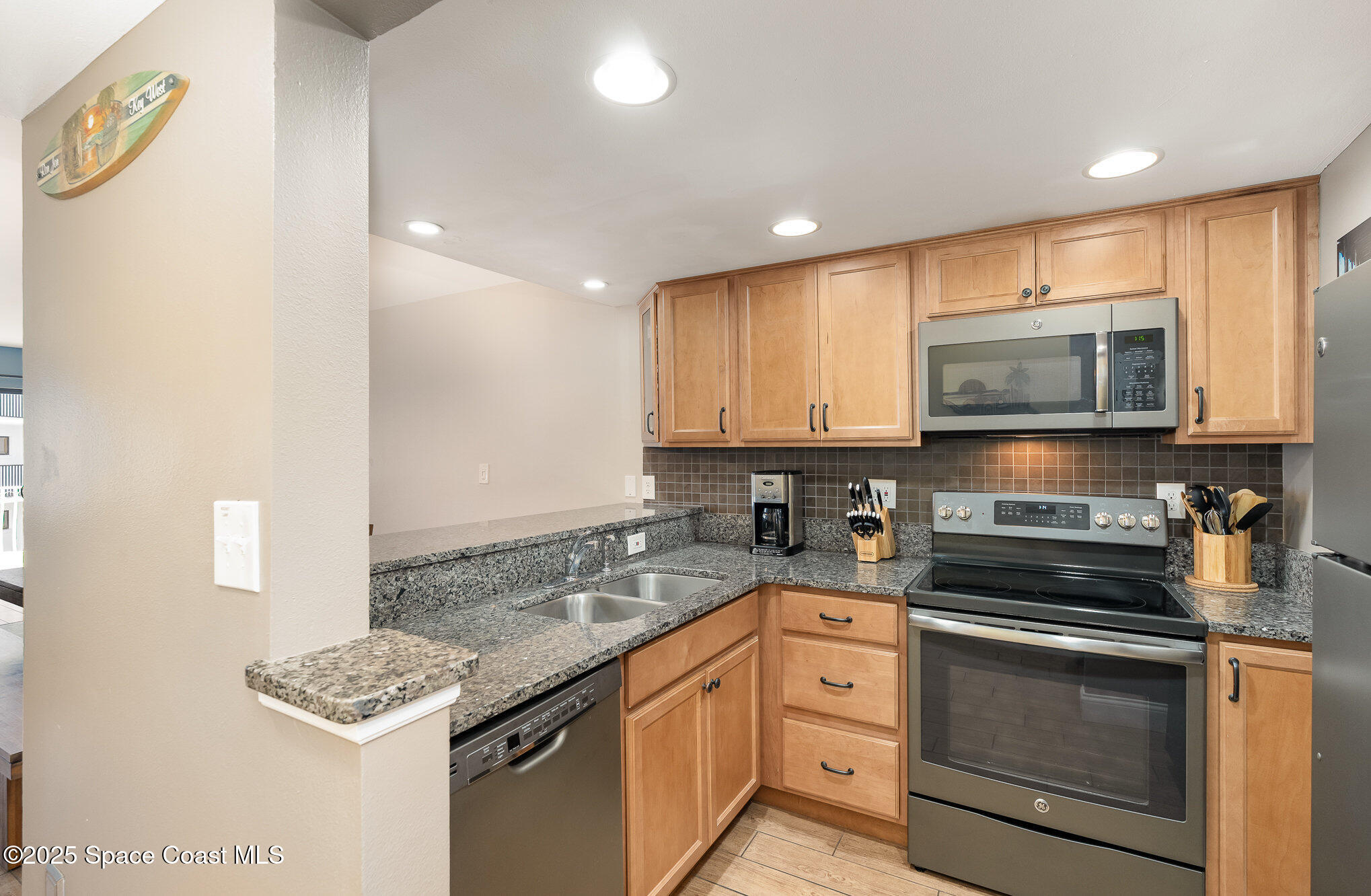 5350 Ocean Beach Boulevard, Unit 211 Cocoa Beach, FL 32931 - Photo 16 of 37 a kitchen with stainless steel appliances granite countertop a stove and a microwave