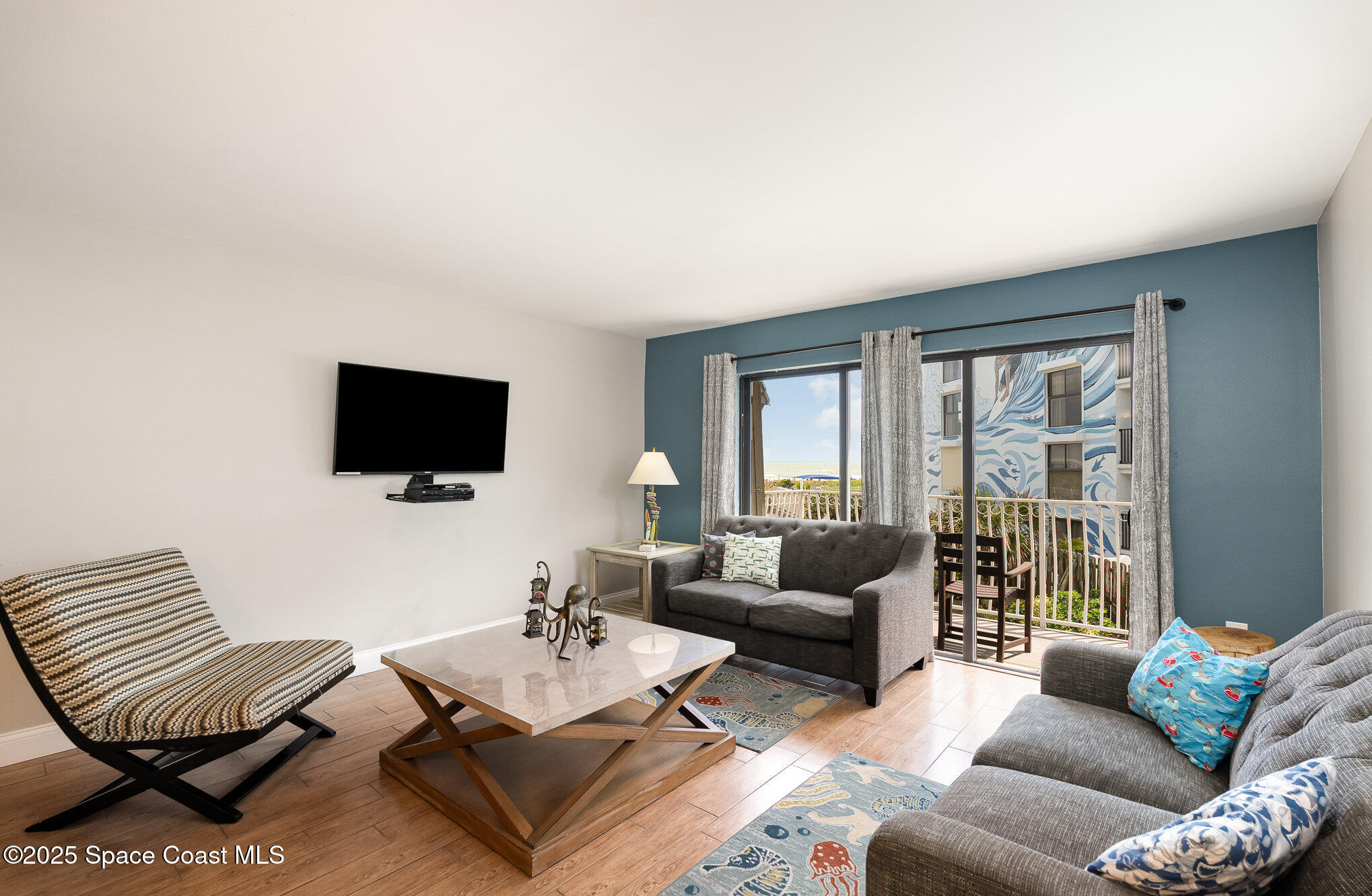 5350 Ocean Beach Boulevard, Unit 211 Cocoa Beach, FL 32931 - Photo 2 of 37 a living room with furniture and a flat screen tv