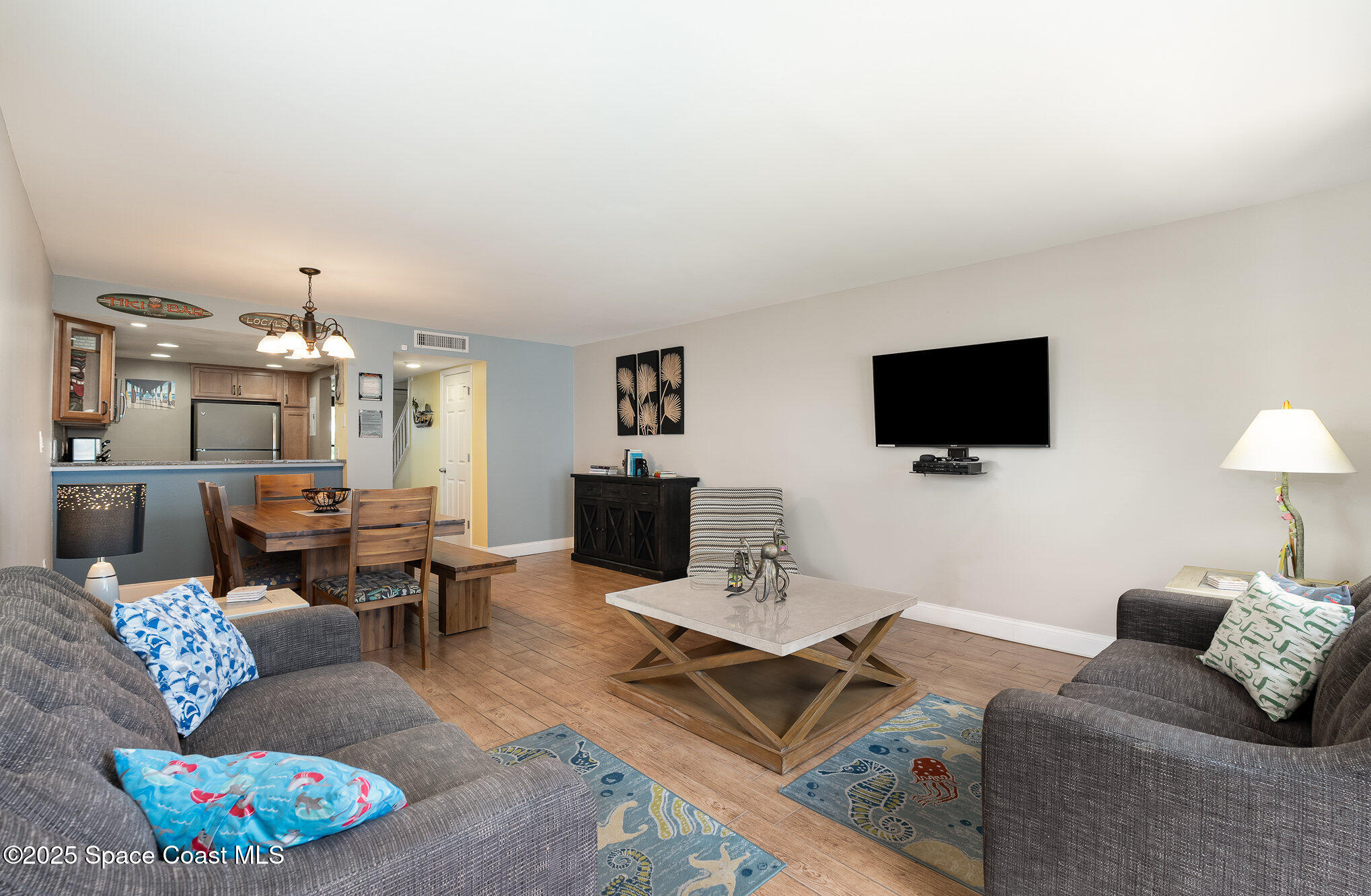 5350 Ocean Beach Boulevard, Unit 211 Cocoa Beach, FL 32931 - Photo 9 of 37 a living room with furniture a flat screen tv and a dining table