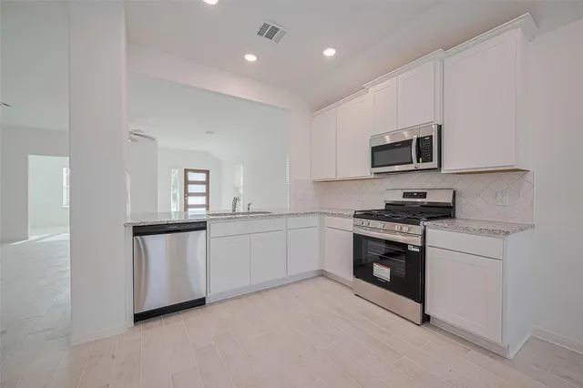 a kitchen with white cabinets and stainless steel appliances