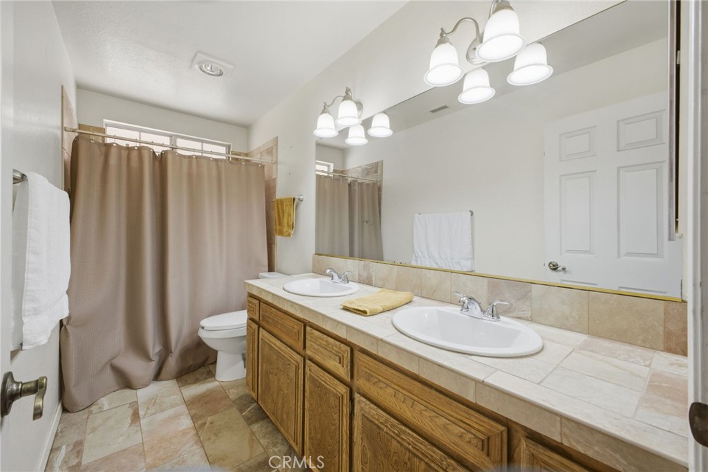 19992 Covell Street Riverside, CA 92508 - Photo 37 of 57 a bathroom with a granite countertop sink a toilet and a mirror