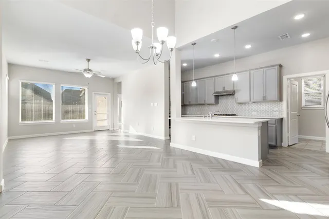 a view of an empty room and kitchen with sink wooden floor and kitchen view
