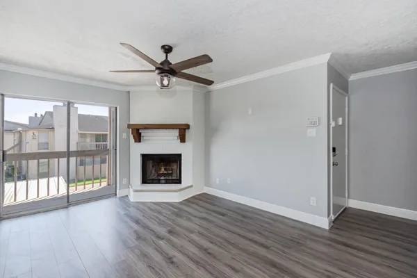 a view of a livingroom with wooden floor a fireplace and windows