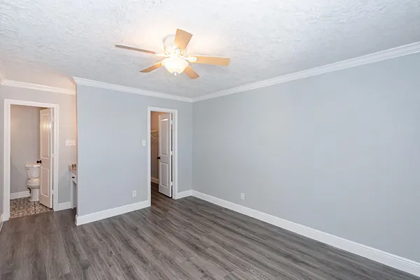 an empty room with wooden floor and ceiling fan