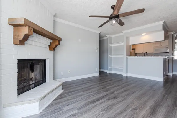 a view of a kitchen with a ceiling fan a fireplace and wooden floor