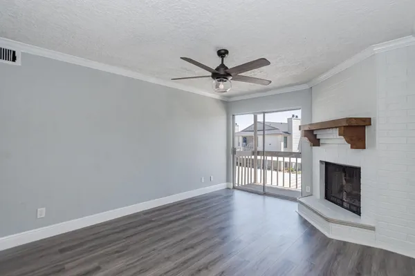 a view of an empty room with wooden floor and a fireplace
