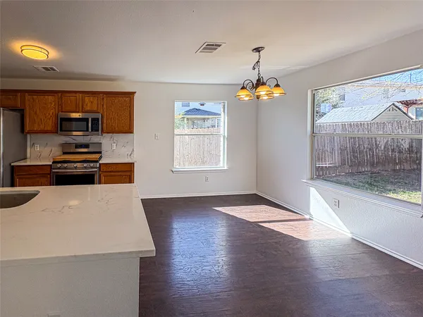 a hallway with a stove a microwave oven and a refrigerator with wooden floor