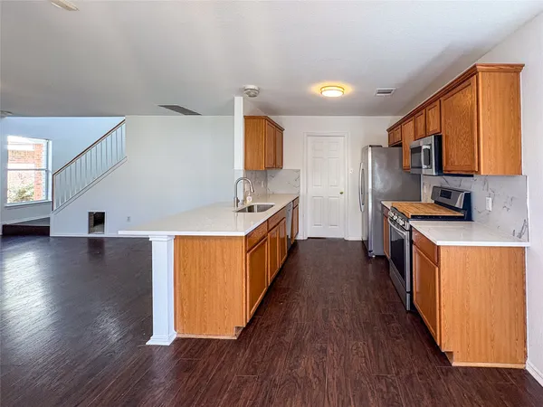 a kitchen with stainless steel appliances a stove top oven a sink a counter space and wooden floor