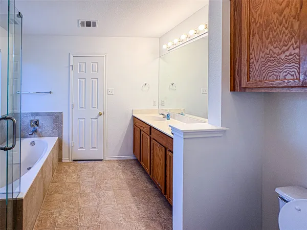 a bathroom with a double vanity sink a toilet and a bathtub
