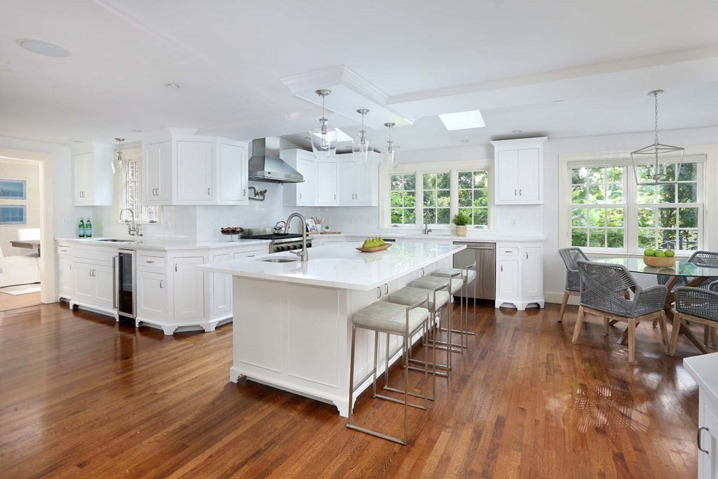 11 Laurel Road Brookline, MA 02467 - Photo 6 of 24 a open kitchen with white cabinets a sink dishwasher and a dining table with wooden floor