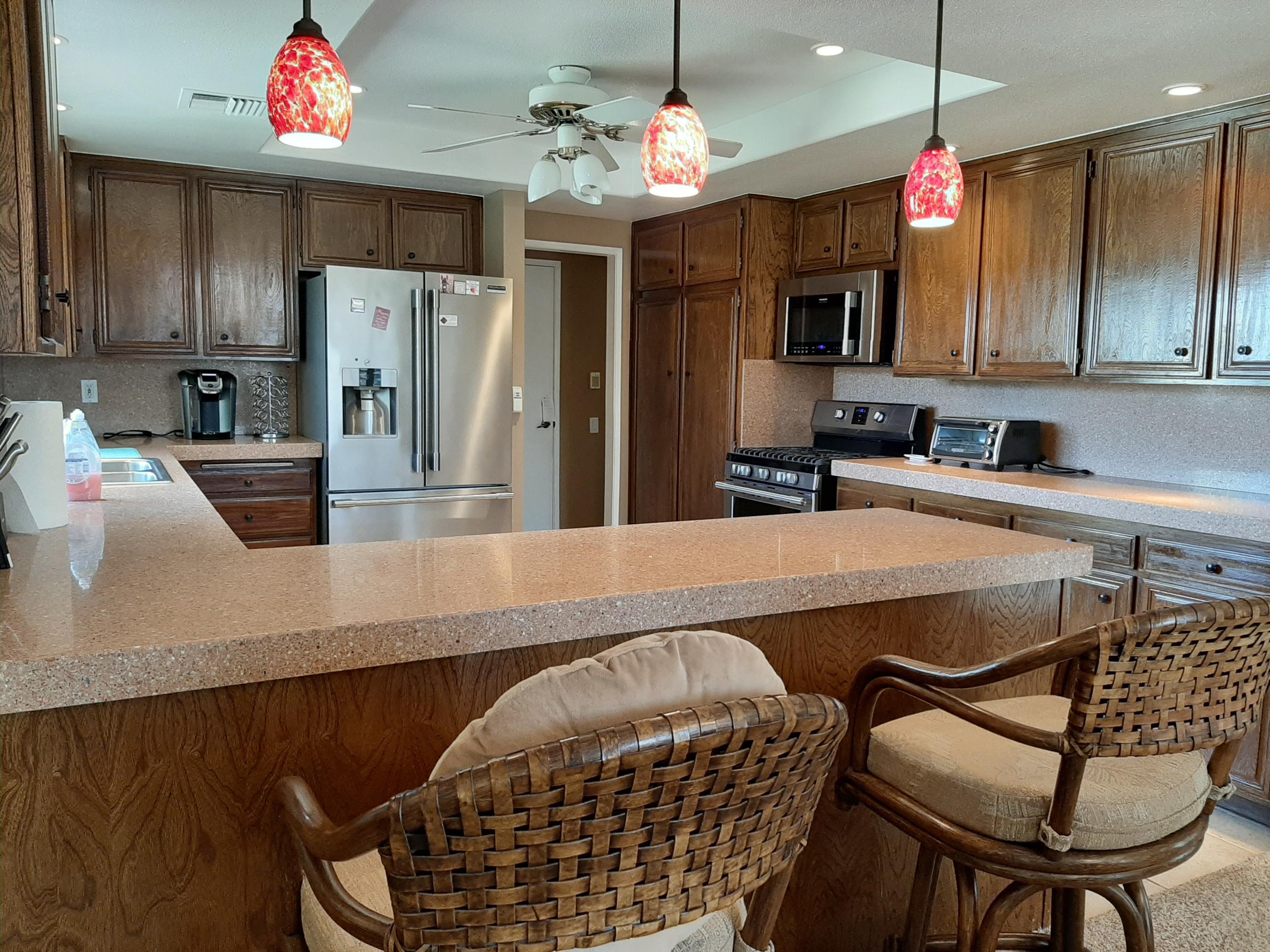 72385 Beverly Way Rancho Mirage, CA 92270 - Photo 1 of 24 a kitchen with stainless steel appliances granite countertop a sink dishwasher a dining table and chairs with wooden floor