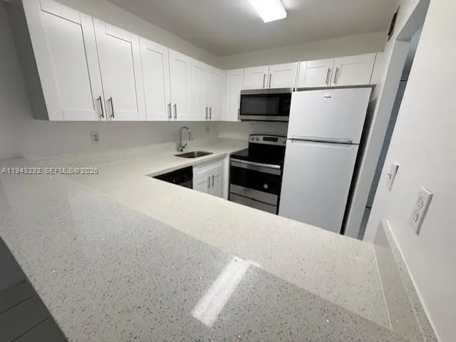 a kitchen with refrigerator a microwave a sink and cabinets