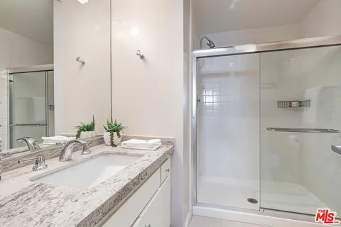 a bathroom with a granite countertop sink mirror and shower