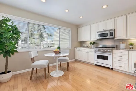 a kitchen with stainless steel appliances a stove a sink a microwave cabinets and a wooden floor