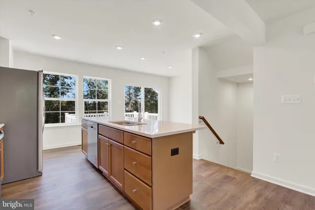 a kitchen with stainless steel appliances granite countertop a stove top oven a sink dishwasher and a refrigerator with wooden floor