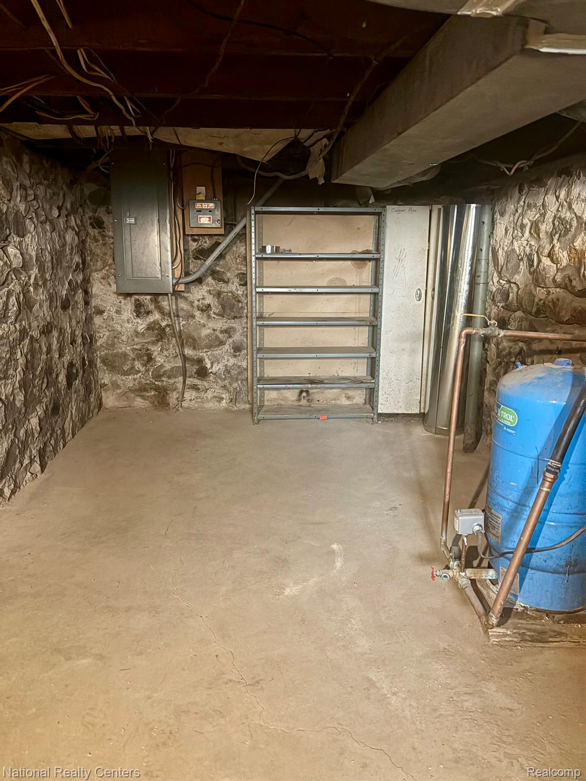 10667 West Sober Road Webberville, MI 48892 - Photo 28 of 28 Unfinished basement featuring exposed stone foundation walls, concrete flooring, and exposed ceiling joists