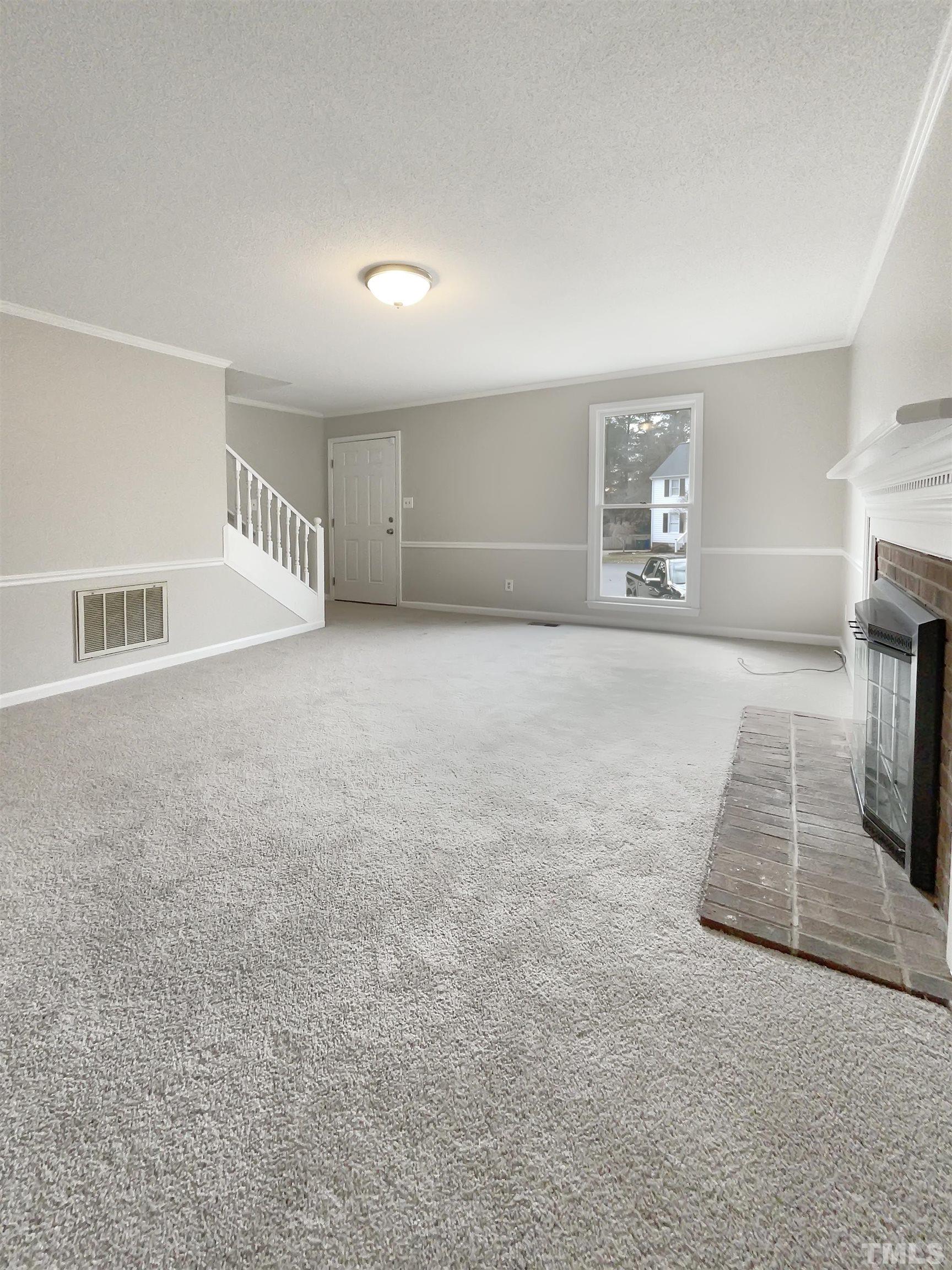 7316 Ewing Place Raleigh, NC 27616 - Photo 4 of 19 an empty room with fireplace and windows