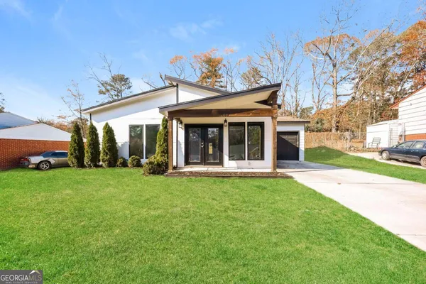a view of a white house with a big yard and potted plants