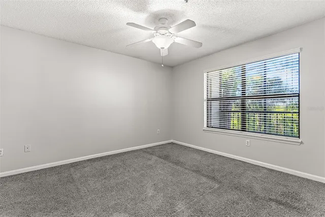 an empty room with windows and chandelier fan
