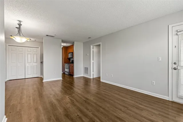 a view of an empty room with wooden floor staircase and a window