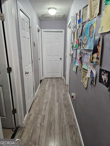 a view of a hallway with wooden floor and closet