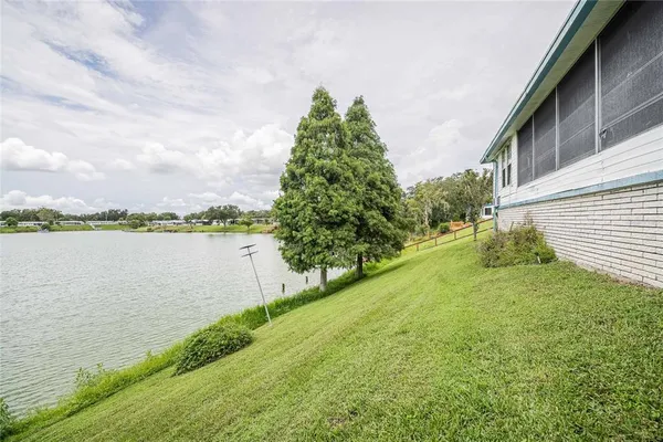 a view of a lake with a big yard and large trees