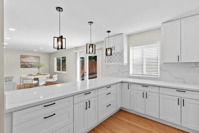 a kitchen with white cabinets and window