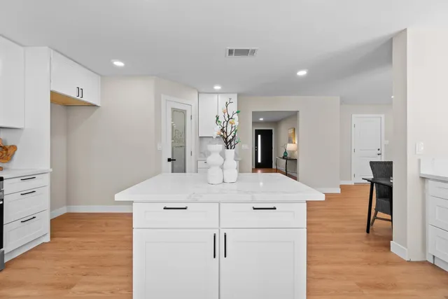 a large white kitchen with kitchen island white cabinets and stainless steel appliances