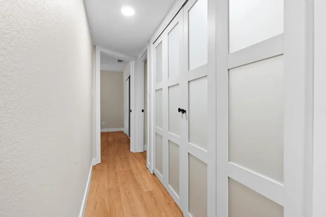 a view of a hallway with white walls and wooden floor