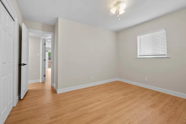 a view of an empty room with wooden floor and a window