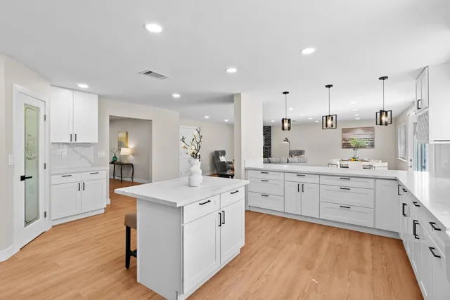 a large white kitchen with a stove a sink dishwasher and a refrigerator with wooden floor