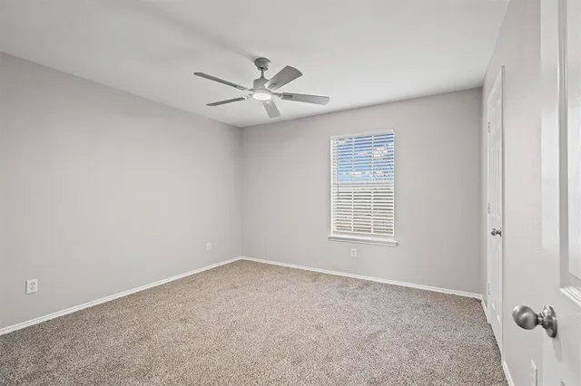 an empty room with a window and ceiling fan