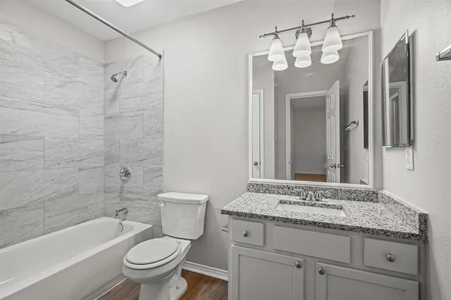 a bathroom with a granite countertop sink a toilet and shower