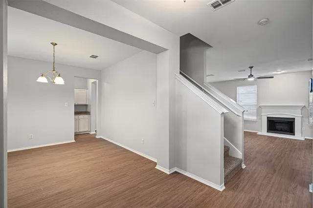 a view of an empty room with wooden floor fireplace and a kitchen